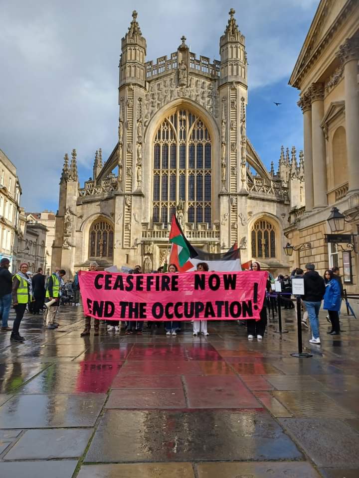 Activists hold a banner in front of Bath Abbey, reading "Ceasefire now, end the occupation"